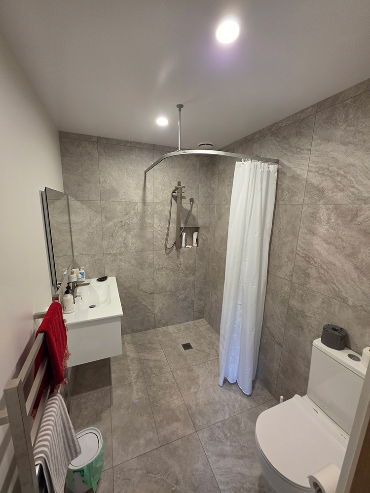 Accessible wet-area shower with curtain and grey tiles