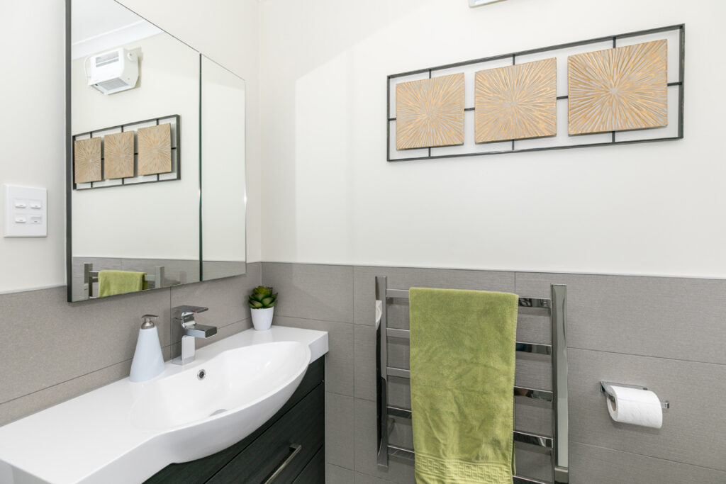 Grey tiled bathroom with vanity and heated towel rail