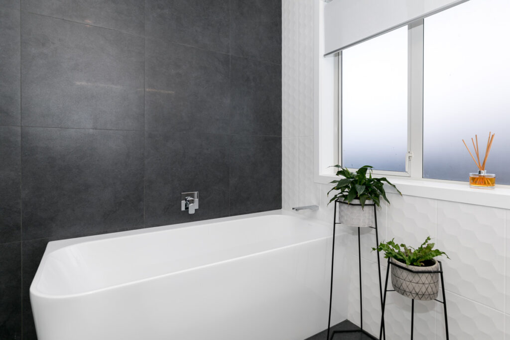 Modern bathroom with back-to-wall bath and dark feature wall
