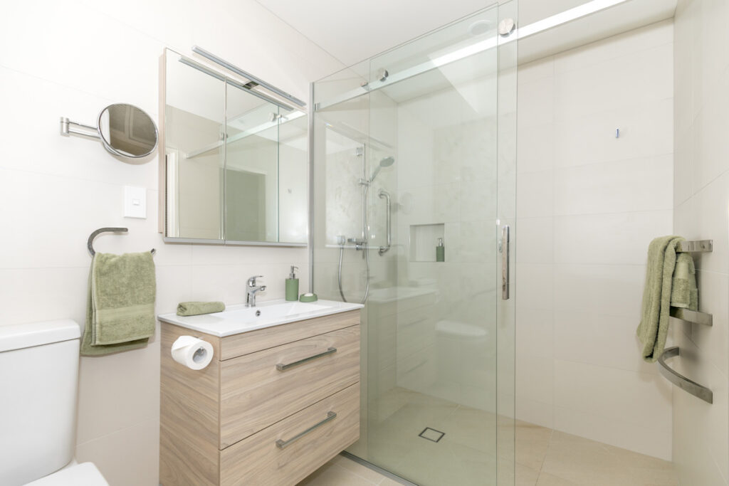 Small bathroom with sliding glass shower and oak vanity