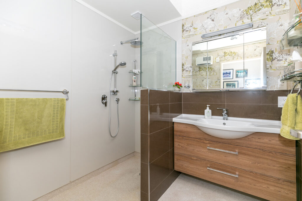 Wide view of a bathroom with timber vanity and walk-in shower